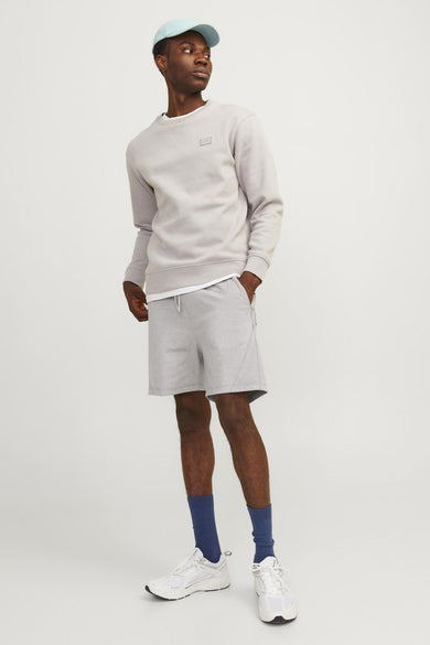 Short de sport gris par JACK & JONES JEANS INTELLIGENCE, porté avec un sweat-shirt et une casquette bleu clair.
