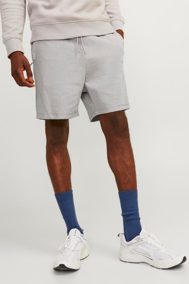Korte grijze van JACK & JONES JEANS INTELLIGENCE gedragen met blauwe sokken en witte sneakers.
