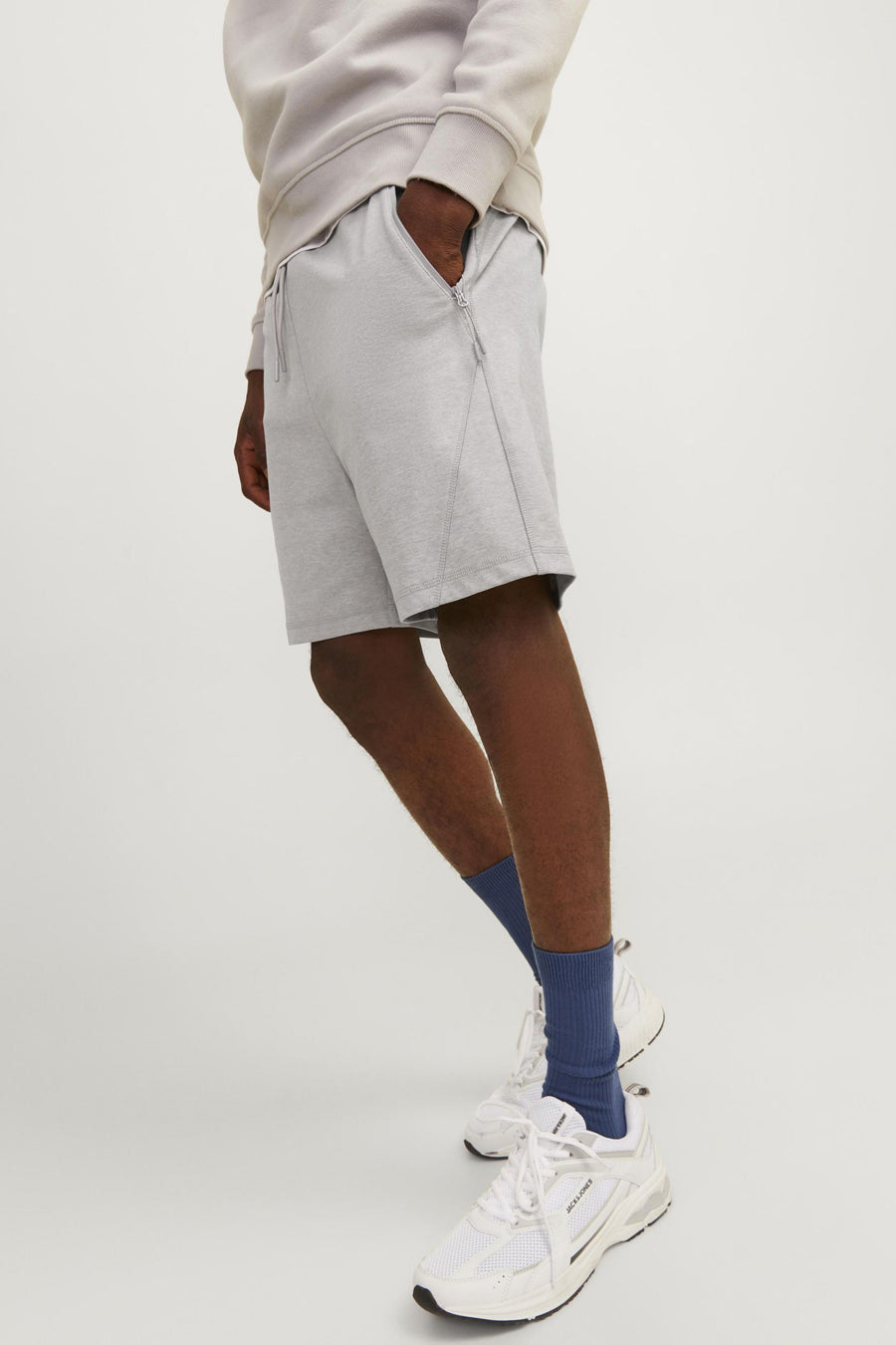Korte grijze short van JACK & JONES JEANS INTELLIGENCE met trekkoord en zijzakken, gedragen met blauwe sokken en witte sneakers.