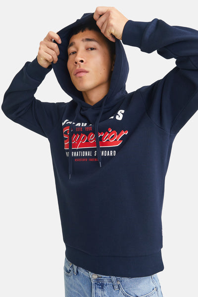 Sweat à capuche bleu marine de Originals by JACK & JONES, avec logo rouge et blanc sur le devant, porté avec un jean.