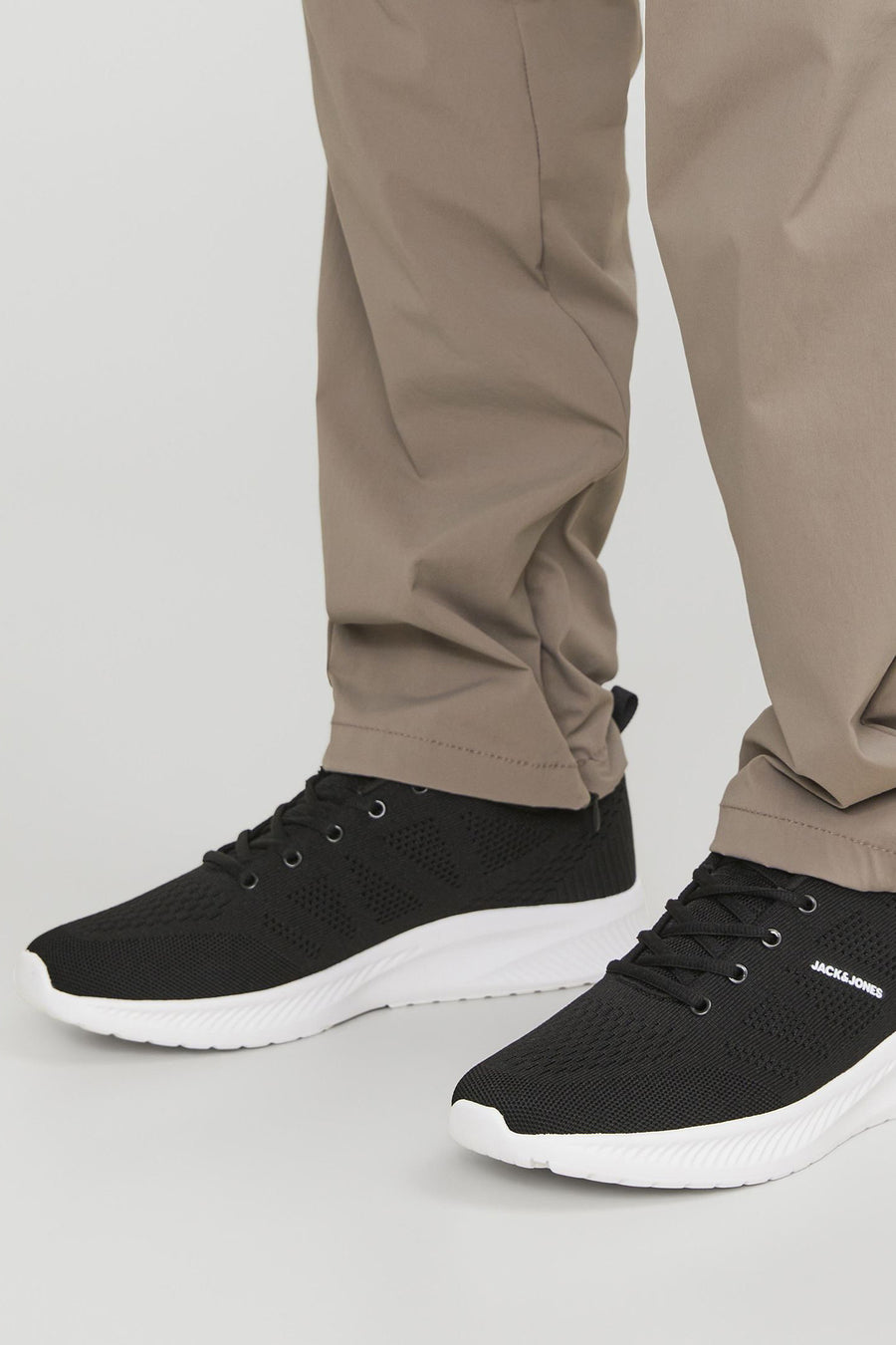 Grijze sneakers van ACCESSORIES BY JACK & JONES, met witte zool en zwarte veters, gedragen met een kaki broek.