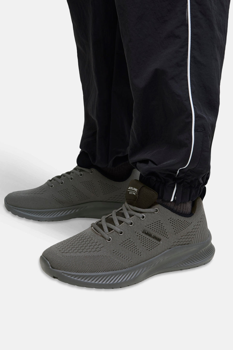 Grijze sneakers van ACCESSORIES BY JACK & JONES, mesh-patroon, gedragen met een zwarte gestreepte broek.