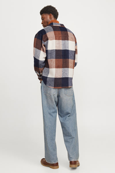 Chemise à manches longues bleue à carreaux, par ORIGINALS BY JACK & JONES, portée avec un jean ample et des chaussures marron.