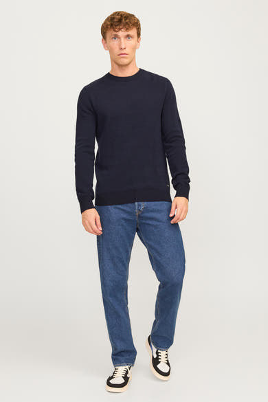 Pull à col rond bleu de JACK & JONES, porté avec un jean bleu et des baskets blanches et noires.
