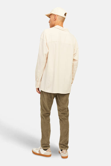 Pantalon marron en velours côtelé de JACK & JONES JEANS INTELLIGENCE, porté avec une chemise beige et des baskets blanches.