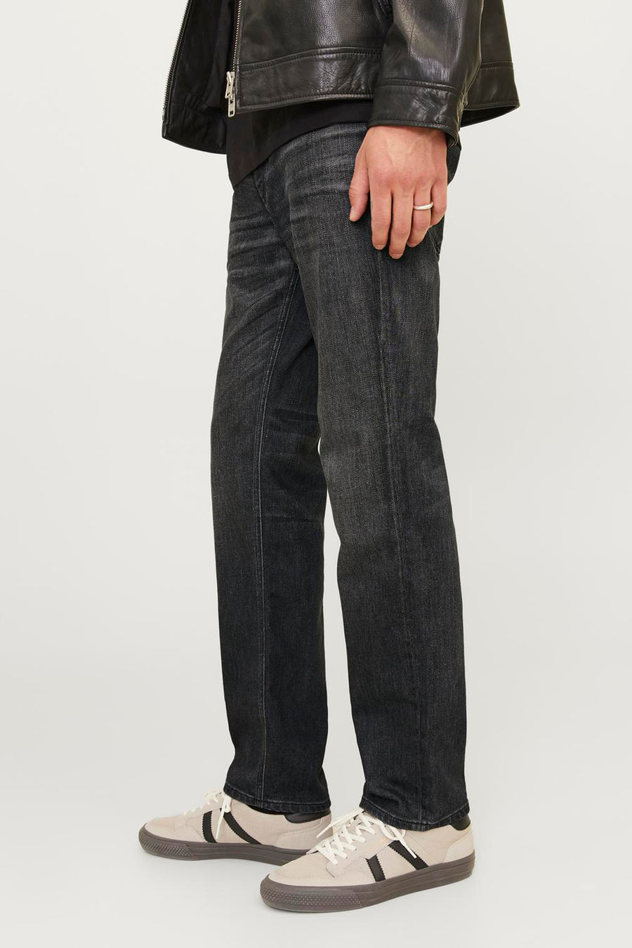 Zwarte rechte jeans van JACK & JONES JEANS INTELLIGENCE, klassieke pasvorm, gedragen met een leren jasje en sneakers.
