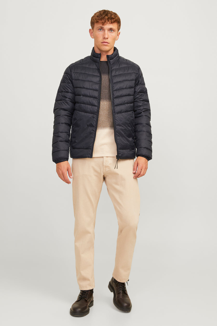 Korte zwarte gewatteerde jas van ORIGINALS BY JACK & JONES, gedragen met een beige trui en een zandkleurige chino.