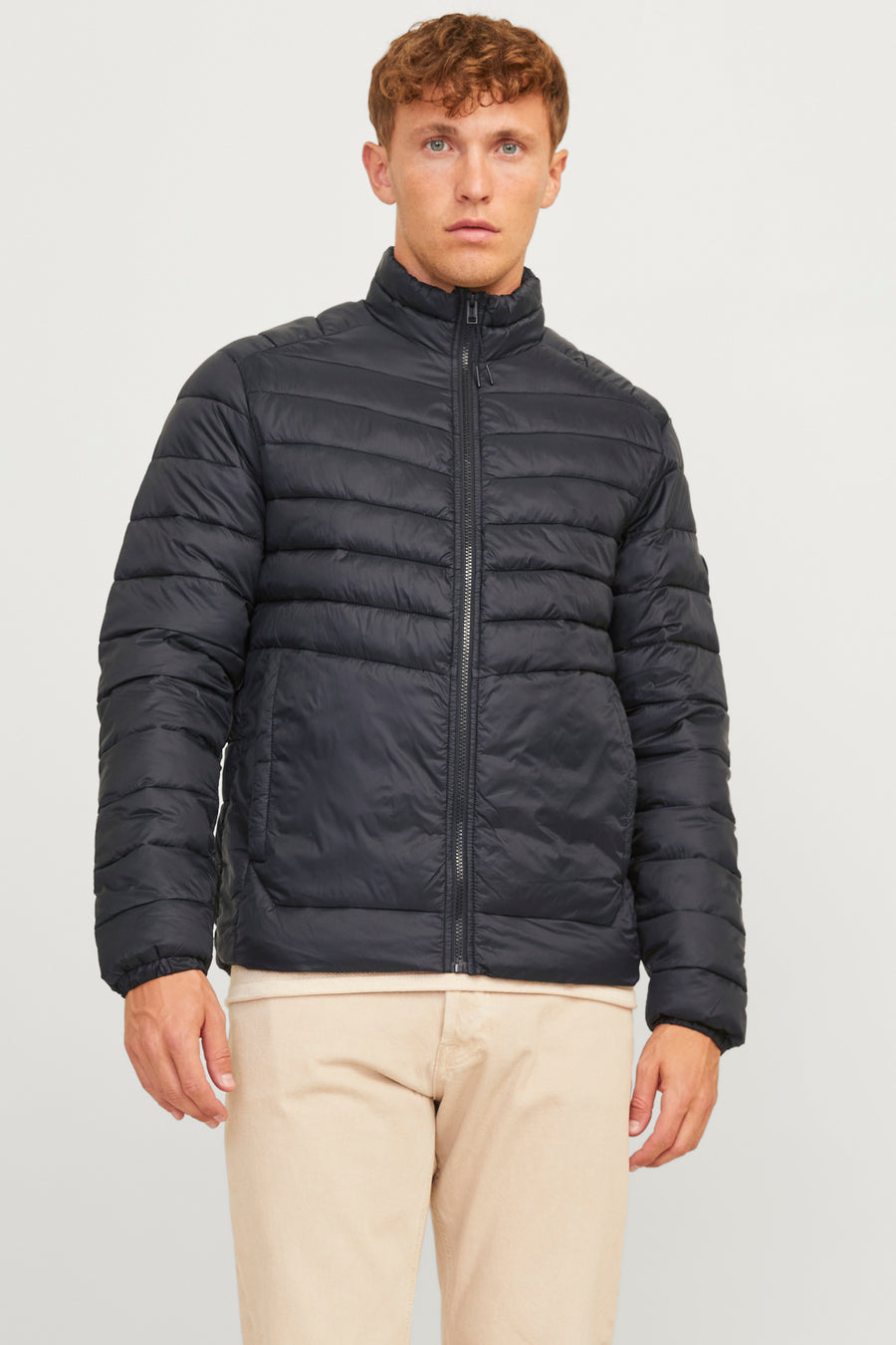 Korte zwarte jas van ORIGINALS BY JACK & JONES, gedragen met een beige broek.