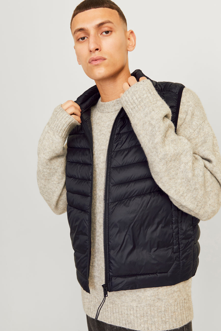 Zwart mouwloos jack van ORIGINALS BY JACK & JONES, gedragen over een dikke gebreide trui.