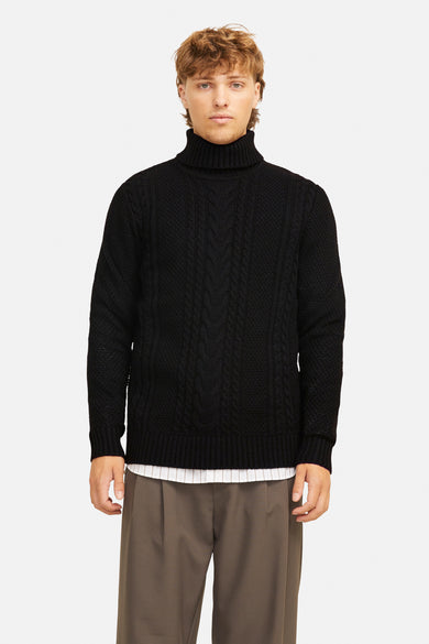 Pull à col roulé noir de JACK & JONES, avec motif torsadé et porté avec un pantalon marron.