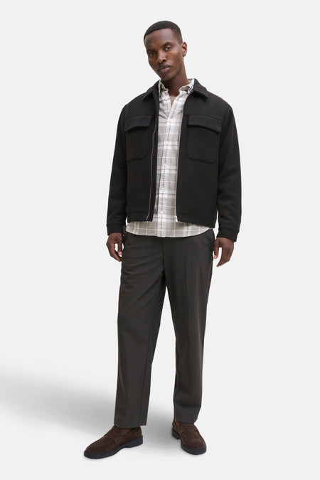 Kort donkerbruin jack van PREMIUM by JACK & JONES, met ritssluiting over een geruit overhemd, bruine broek en schoenen.