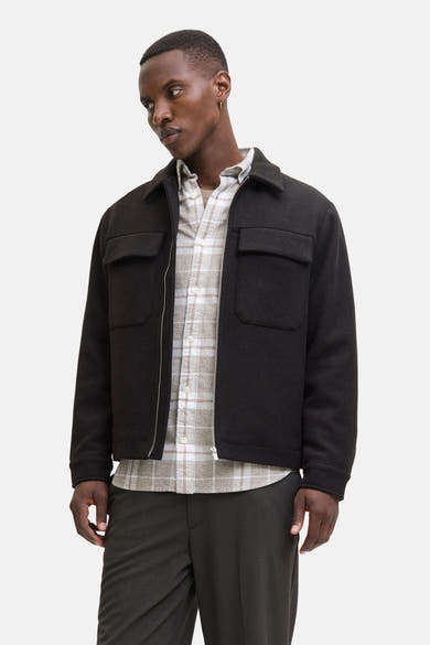 Kort bruin jack van PREMIUM by JACK & JONES gedragen over een geruit overhemd, met een donkere broek.