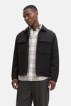 Kort bruin jack van PREMIUM by JACK & JONES gedragen over een geruit overhemd, met een donkere broek.