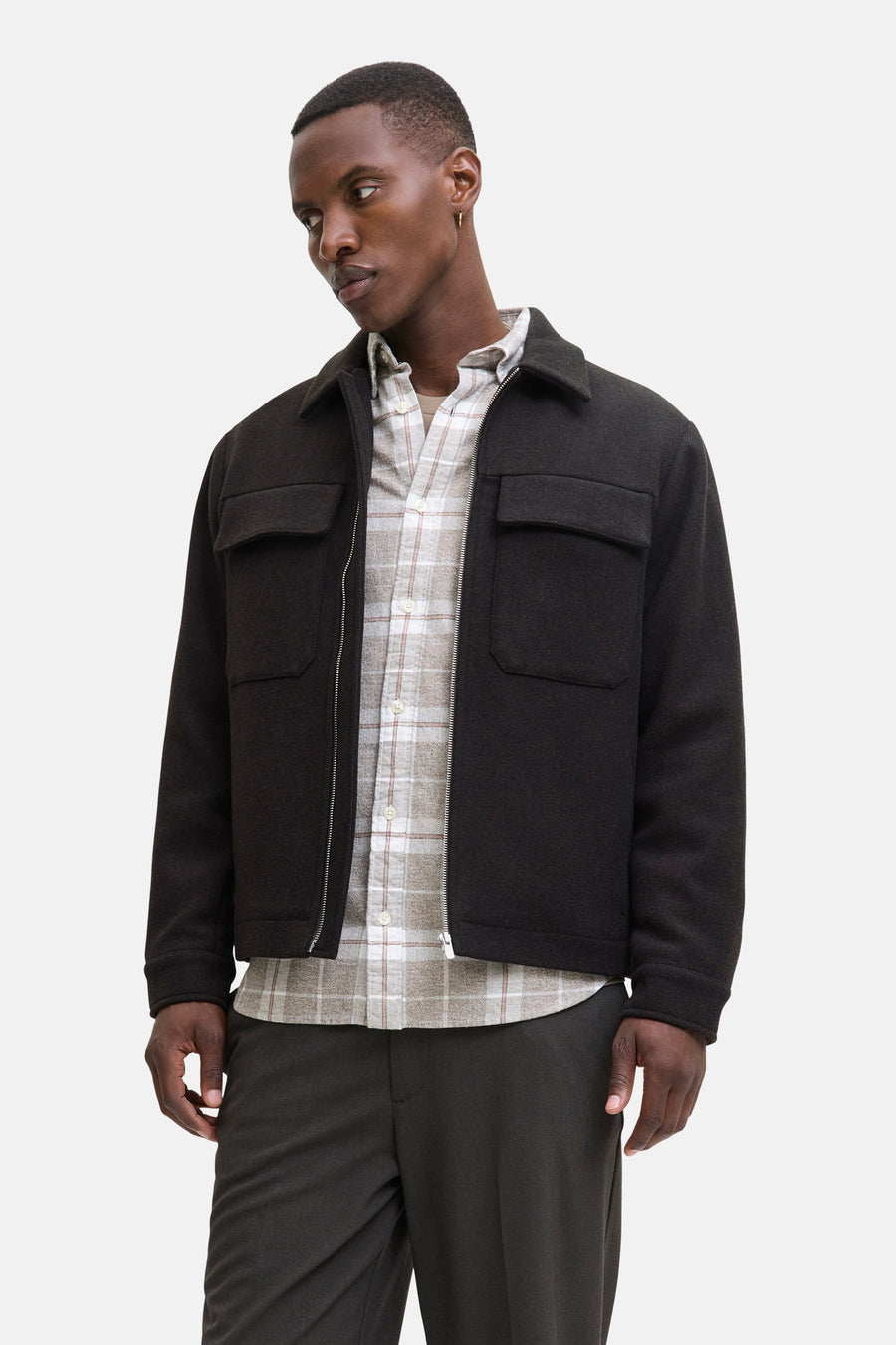 Kort bruin jack van PREMIUM by JACK & JONES gedragen over een geruit overhemd, met een donkere broek.