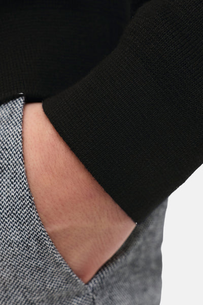 Pull à col roulé noir de PREMIUM by JACK & JONES, avec une manche texturée et un pantalon à carreaux gris.
