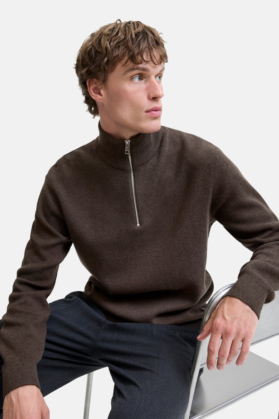 Brown ribbed knit turtleneck sweater with front zipper, side view on model wearing dark trousers