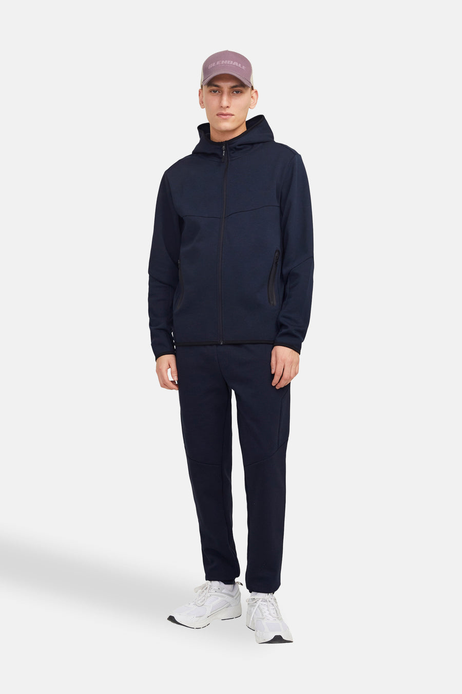 Donkerblauwe hoodie van JACK & JONES, gedragen met een joggingbroek en een pet.