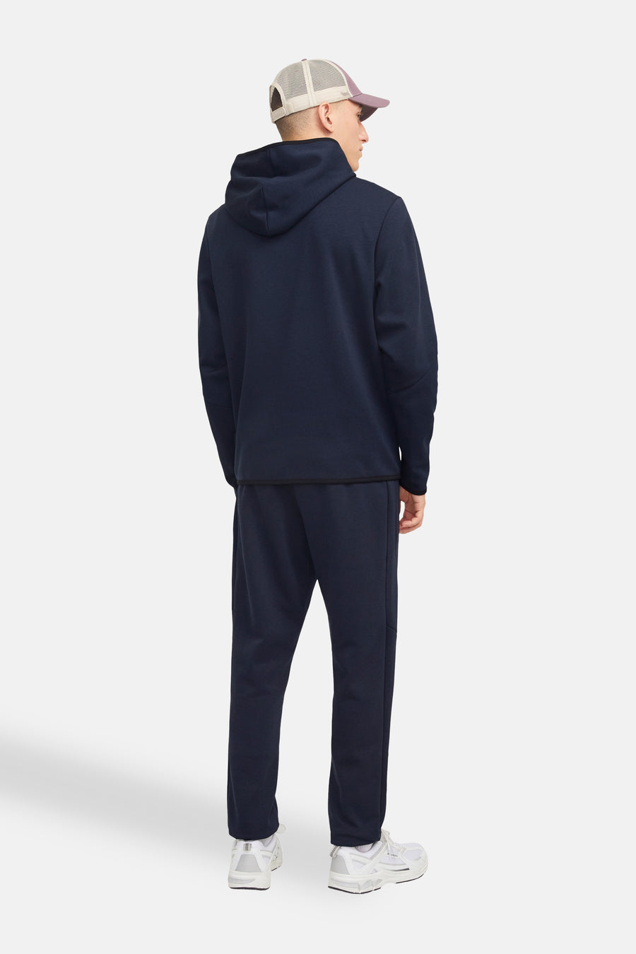 Donkerblauwe hoodie van JACK & JONES, gedragen met een bijpassende joggingbroek en een pet.