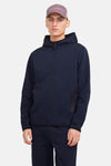 Donkerblauwe bodywarmer van JACK & JONES, met capuchon en volledige ritssluiting, gedragen met een bijpassende joggingbroek.