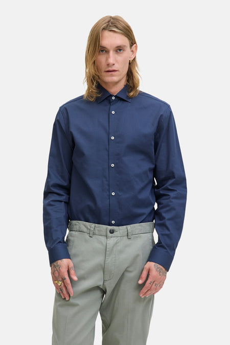 Blauwe blouse met lange mouwen van PREMIUM by JACK & JONES, gedragen met een grijze broek, zichtbaar op een man met lang haar.