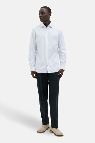 Wit overhemd met lange mouwen van PREMIUM by JACK & JONES, met subtiele verticale strepen, gedragen met een zwarte broek en suède schoenen.