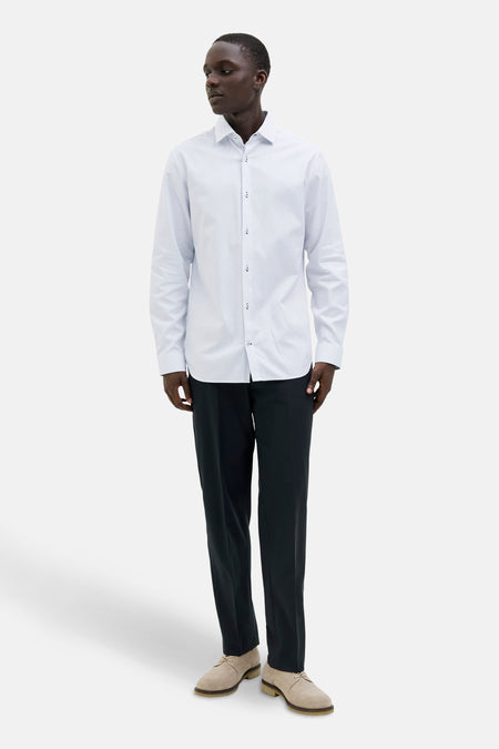 Wit overhemd met lange mouwen van PREMIUM by JACK & JONES, met subtiele verticale strepen, gedragen met een zwarte broek en suède schoenen.