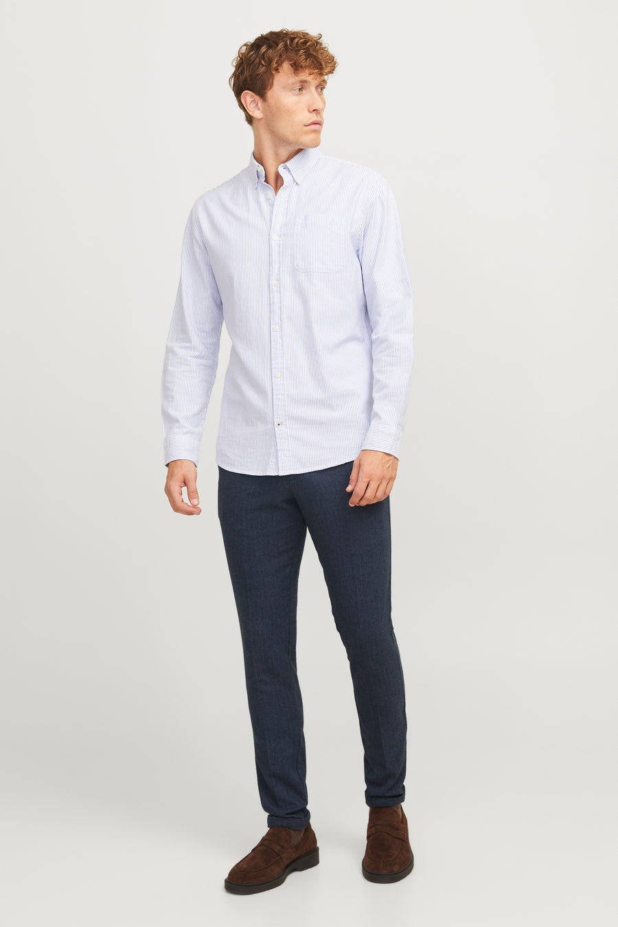 Pantalon de costume bleu JACK & JONES, avec une texture subtile, porté avec une chemise rayée et des mocassins marron.
