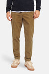 Pantalon de costume beige en velours côtelé par JACK & JONES, ajusté, porté avec un pull marine et des sneakers claires, vue de face.