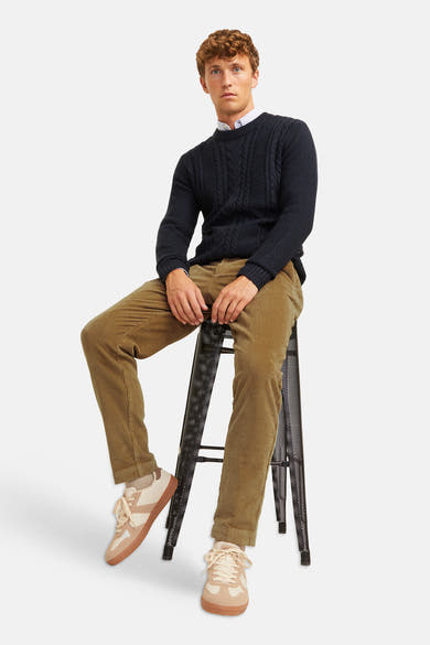 Pantalon de costume beige en velours côtelé par JACK & JONES, porté avec un pull marine et des baskets claires, vue de face lifestyle