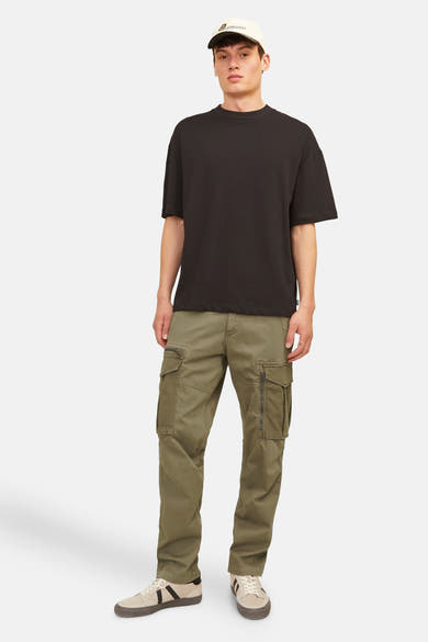 Kaki cargobroek van Jack & Jones, met ritszakken en robuuste afwerking, gedragen met een zwart T-shirt en beige sneakers.