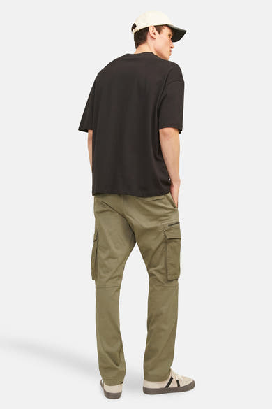 Kaki cargobroek van JACK & JONES, gedragen met een oversized zwart T-shirt en beige sneakers.