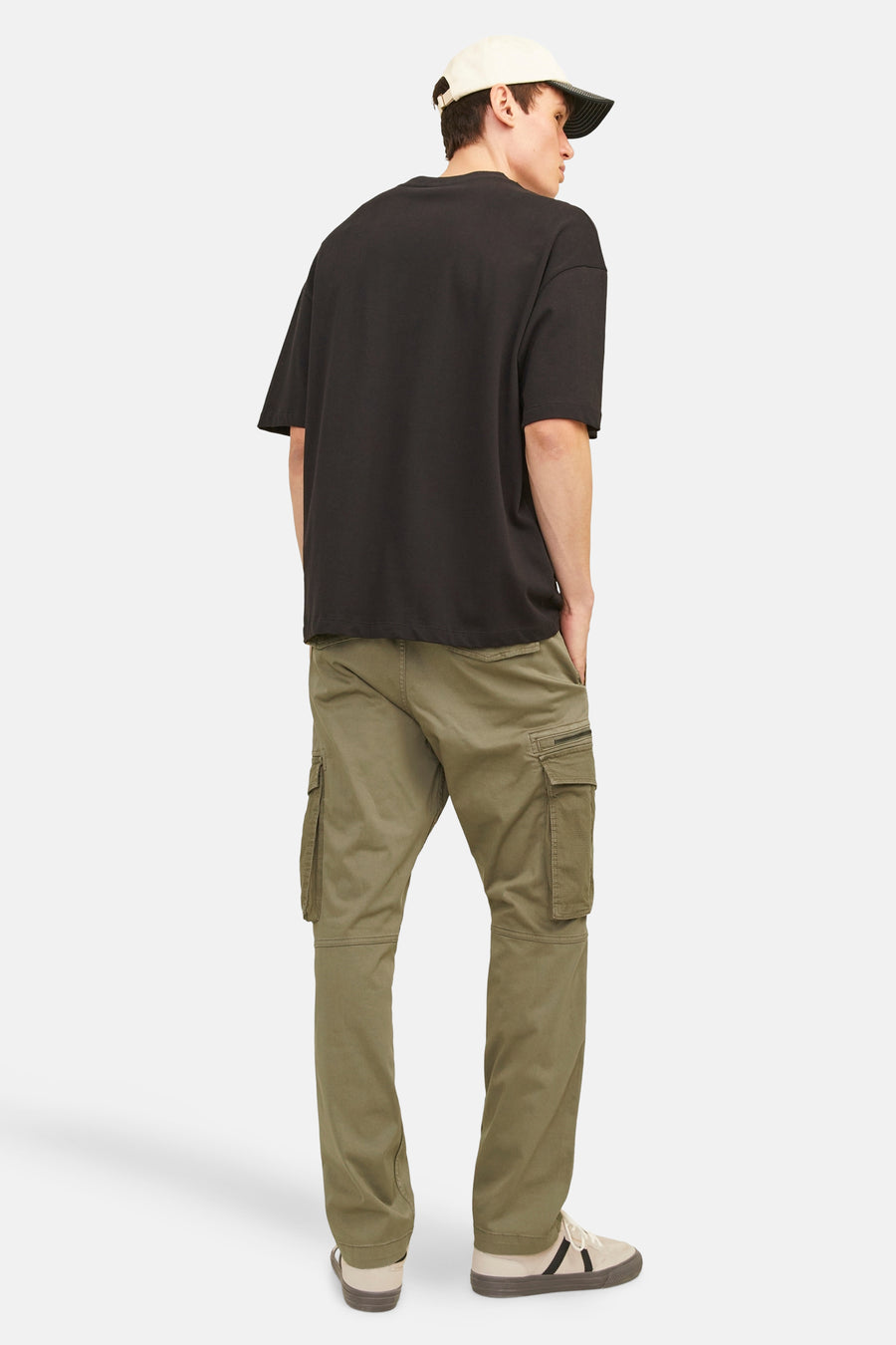 Kaki cargobroek van JACK & JONES, gedragen met een oversized zwart T-shirt en beige sneakers.
