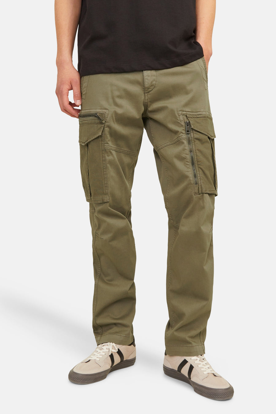 Kaki cargobroek van JACK & JONES, met zakken met rits en gedragen met een zwart T-shirt en beige sneakers.
