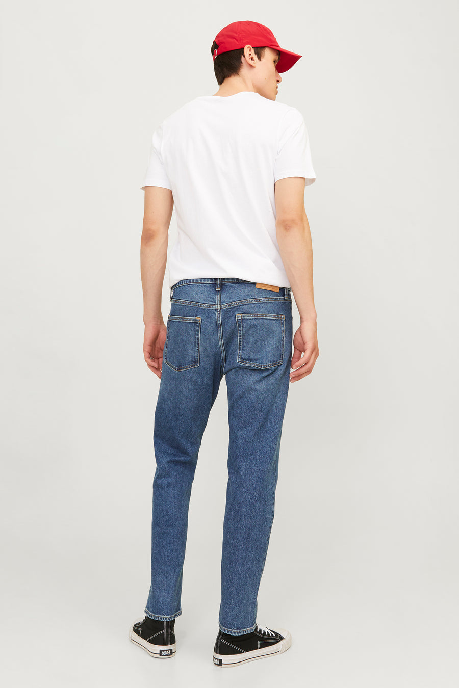 Jack & Jones middellange blauwe tapered jeans, met achterzakken en zwarte schoenen.
