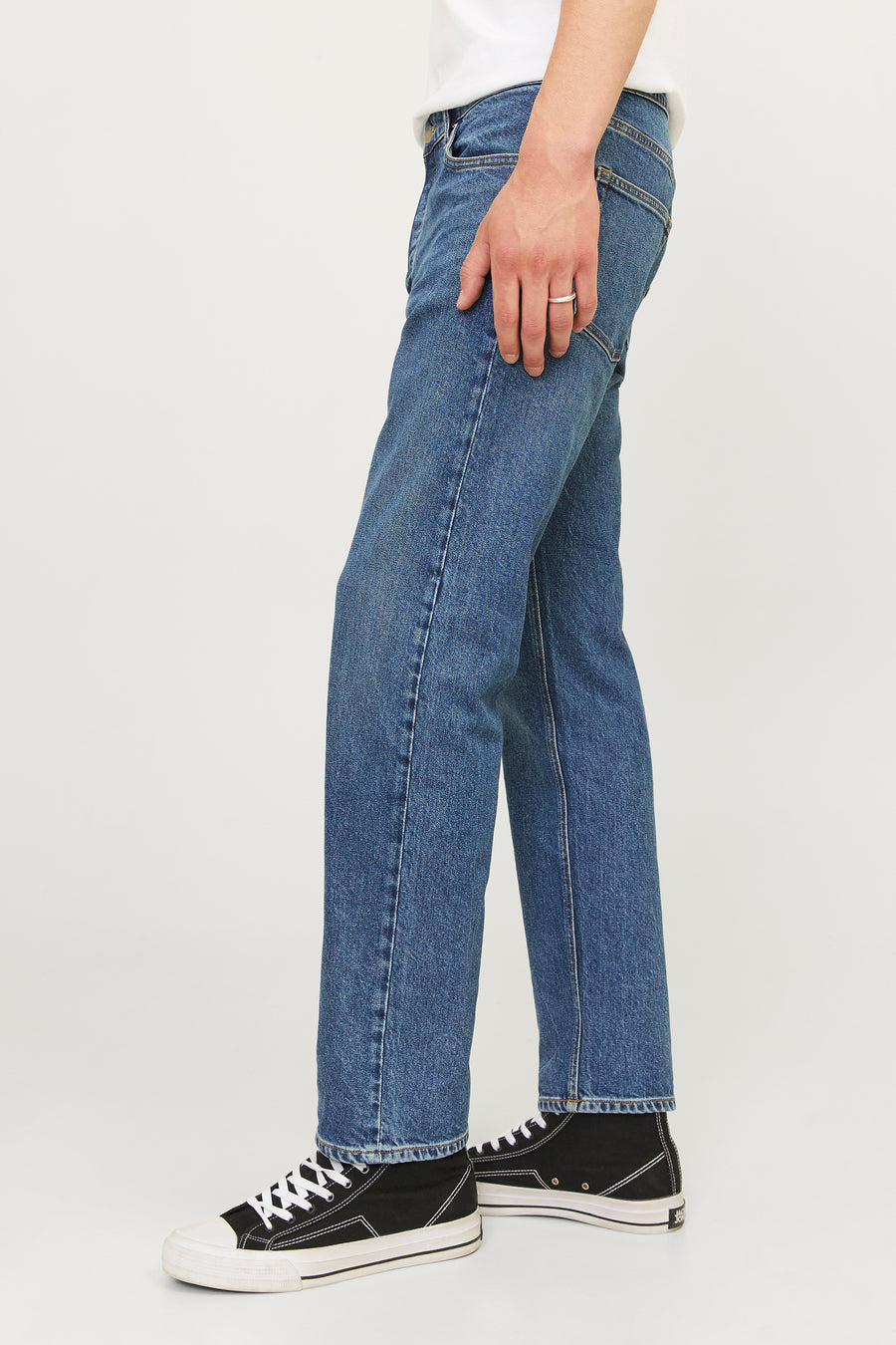 Taps toelopende jeans van middendonkerblauw denim van JACK & JONES, gedragen met zwart-witte hoge sneakers.