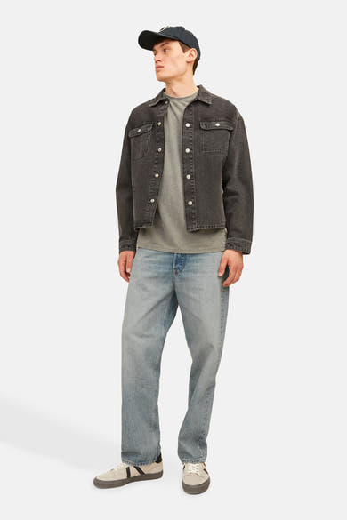Wijde spijkerbroek in lichtblauw denim van Jack & Jones Jeans Intelligence, gedragen met een zwart jasje en beige sneakers.