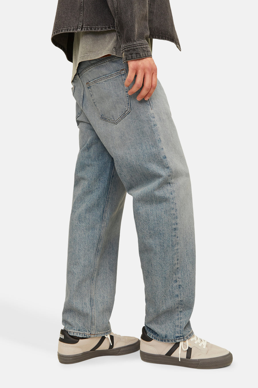 Wijde spijkerbroek in lichtblauw denim van JACK & JONES, gedragen met een grijs jasje en sneakers.
