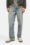 Wijde spijkerbroek in lichtblauw denim van JACK & JONES, gedragen met een grijs T-shirt en een zwarte jas.