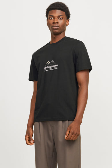 T-shirt noir à manches courtes de JACK & JONES, avec un logo graphique centré sur le devant, porté avec un pantalon marron plissé.