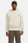 Witte hoodie Originals van JACK & JONES, gedragen met een bruine broek en een blauwe pet.