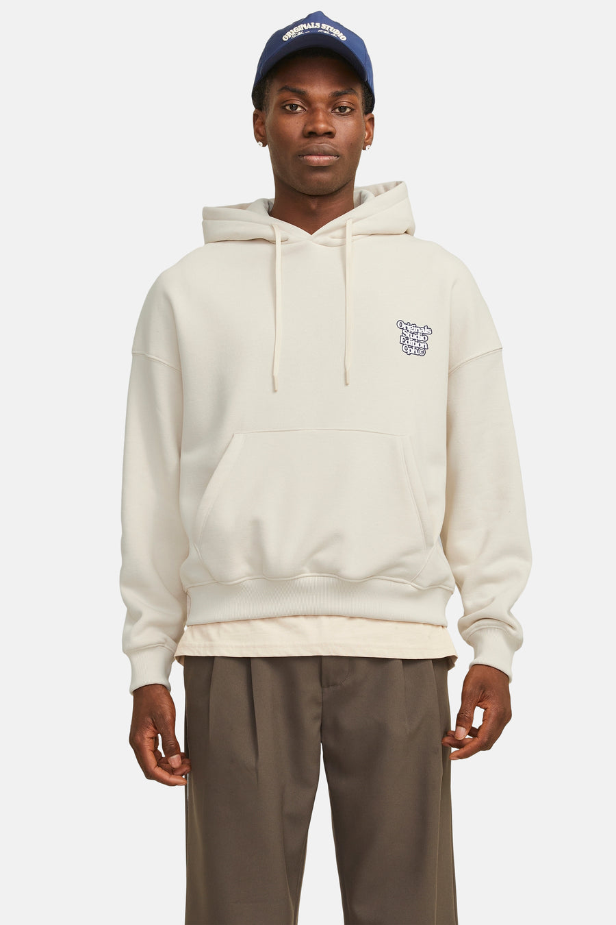 Witte hoodie Originals van JACK & JONES, gedragen met een bruine broek en een blauwe pet.