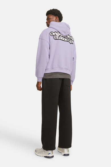 Paarse hoodie van ORIGINALS BY JACK & JONES, met print op de rug, gedragen met een zwarte broek.