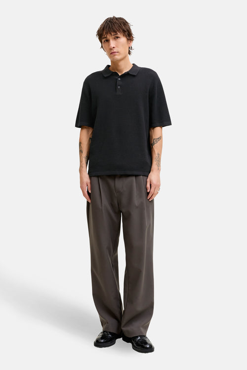 Zwarte textuur trui van JACK & JONES, gedragen met een wijde grijze broek en zwarte schoenen.
