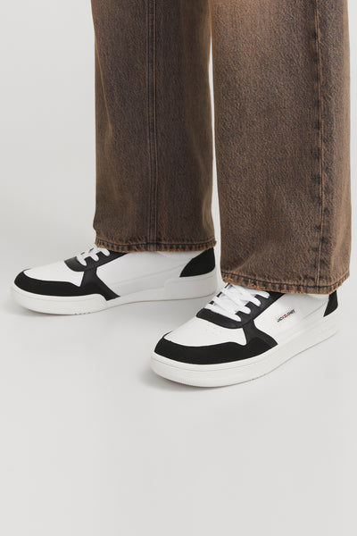 Zwart-witte sneakers van ACCESSORIES BY JACK & JONES met veters en witte zool, gedragen met een lichtbruine jeans.