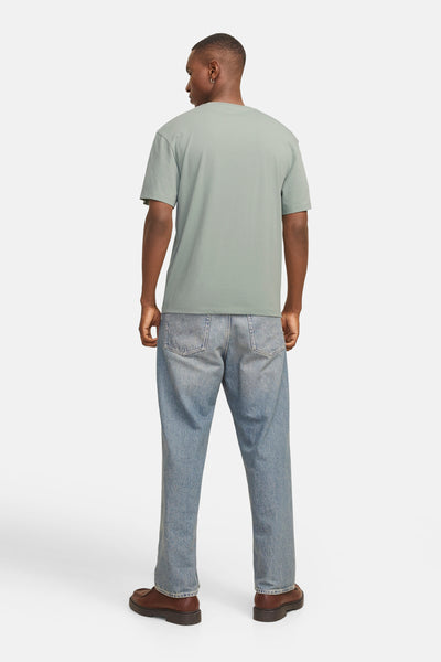 T-shirt à manches courtes vert de JACK & JONES, avec des jeans délavés et des chaussures marron.