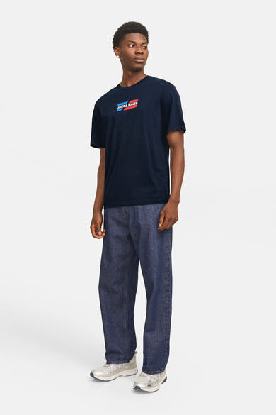 Blauw T-shirt met korte mouwen van JACK & JONES, gedragen met een wijde blauwe jeans en grijze sneakers.