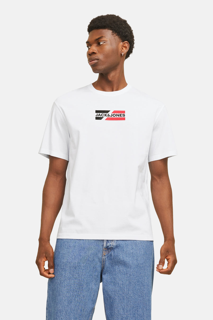 T-shirt blanc à manches courtes de JACK & JONES, avec un logo rectangulaire sur la poitrine et un jean bleu porté.
