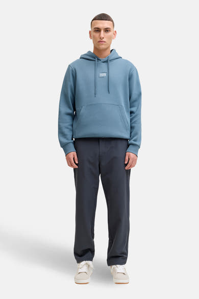 Sweat à capuche bleu par JACK & JONES, avec cordon de serrage, poche kangourou et pantalon sombre.