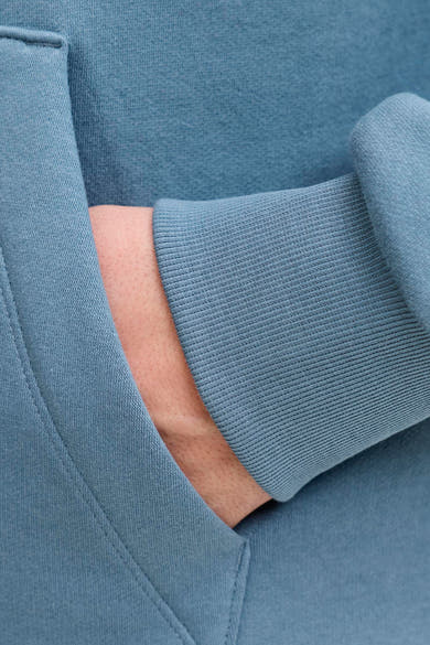 Sweat à capuche bleu de JACK & JONES, avec poignet côtelé et main dans la poche.
