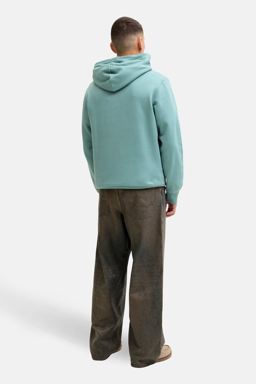 Blauwe hoodie van JACK & JONES, van achteren getoond met een losse bruine broek en suède schoenen.